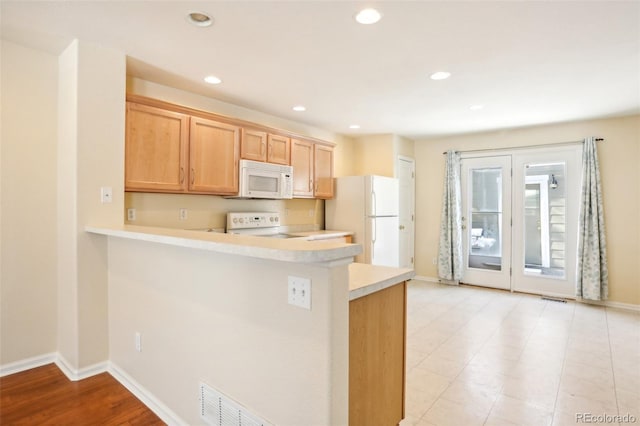 kitchen with kitchen peninsula, light brown cabinets, white appliances, and light wood-type flooring