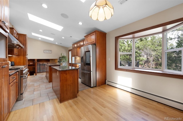 6535 Arequa Ridge Ln, Colorado Springs, CO 80919 - kitchen with baseboard heating, vaulted ceiling with skylight, stainless steel appliances, under cabinet range hood, and a kitchen island