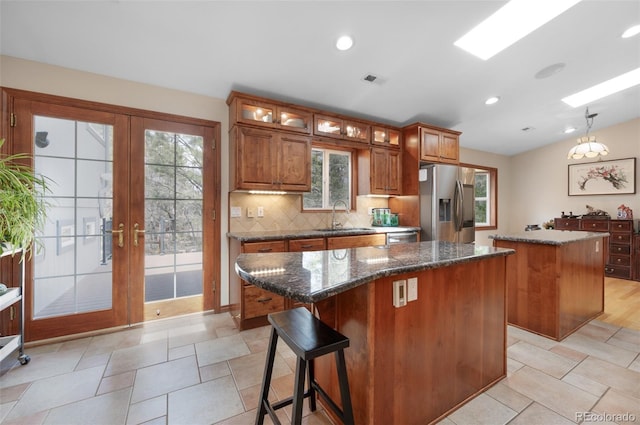 6535 Arequa Ridge Ln, Colorado Springs, CO 80919 - kitchen with brown cabinets, a sink, stainless steel fridge with ice dispenser, a center island, and tasteful backsplash