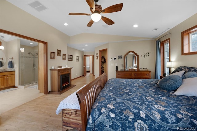 6535 Arequa Ridge Ln, Colorado Springs, CO 80919 - bedroom featuring a lit fireplace, visible vents, light wood-type flooring, lofted ceiling, and ensuite bathroom