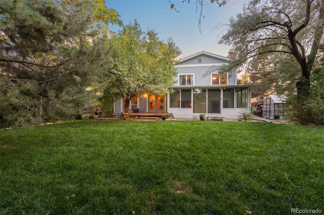 back of property featuring a sunroom, a yard, and an outdoor structure