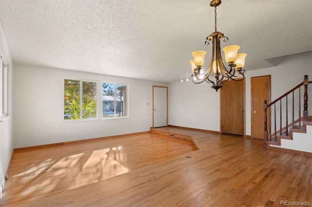 interior space featuring a textured ceiling, hardwood / wood-style flooring, and a notable chandelier