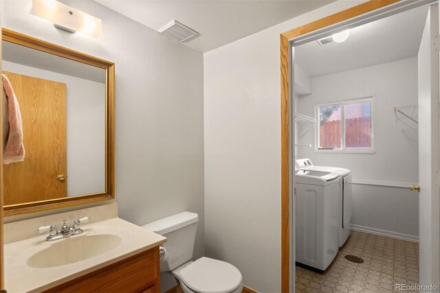 bathroom with vanity, washing machine and dryer, and toilet