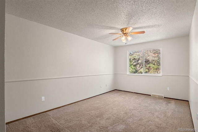 carpeted spare room featuring ceiling fan and a textured ceiling