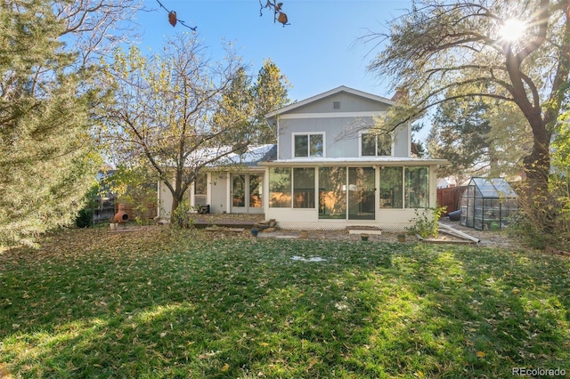 back of house with a lawn, a sunroom, and an outbuilding