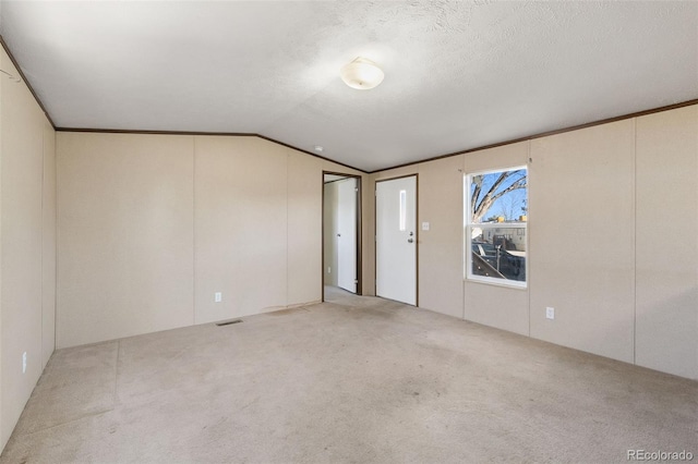 carpeted empty room with a textured ceiling and vaulted ceiling