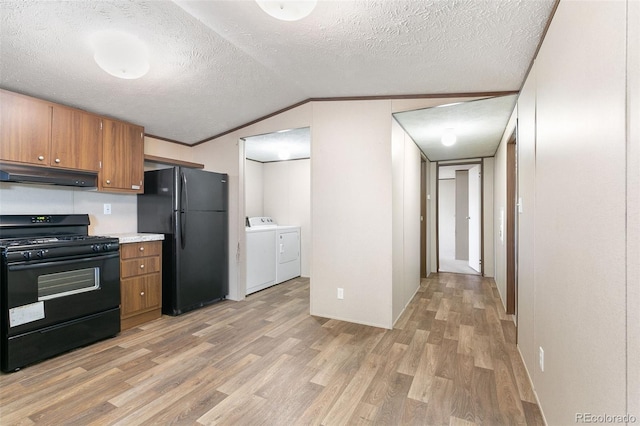 kitchen with light wood-type flooring, a textured ceiling, black appliances, washing machine and clothes dryer, and lofted ceiling