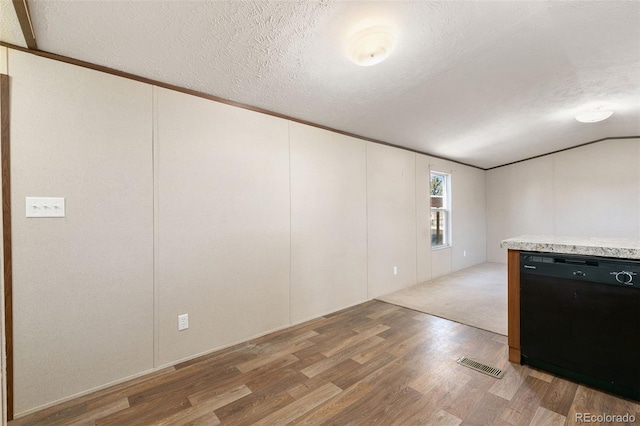 empty room with a textured ceiling, light hardwood / wood-style floors, vaulted ceiling, and ornamental molding