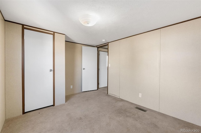 unfurnished bedroom featuring a textured ceiling and light colored carpet