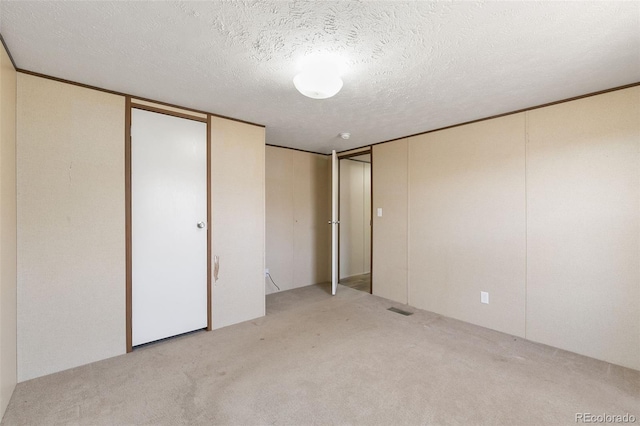 unfurnished bedroom featuring light carpet and a textured ceiling