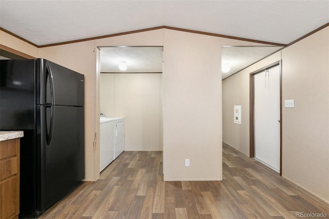 kitchen featuring dark hardwood / wood-style floors, black refrigerator, lofted ceiling, and independent washer and dryer