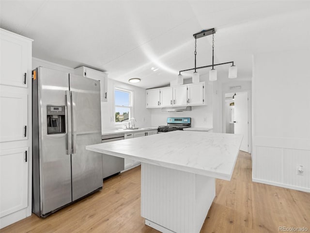 kitchen featuring pendant lighting, appliances with stainless steel finishes, a center island, white cabinetry, and sink