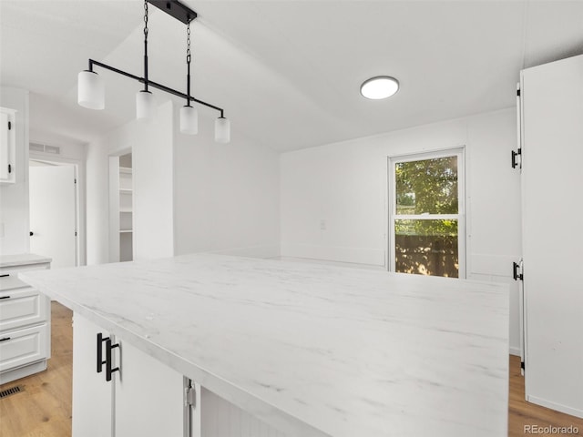 kitchen featuring white cabinets, decorative light fixtures, and light hardwood / wood-style floors