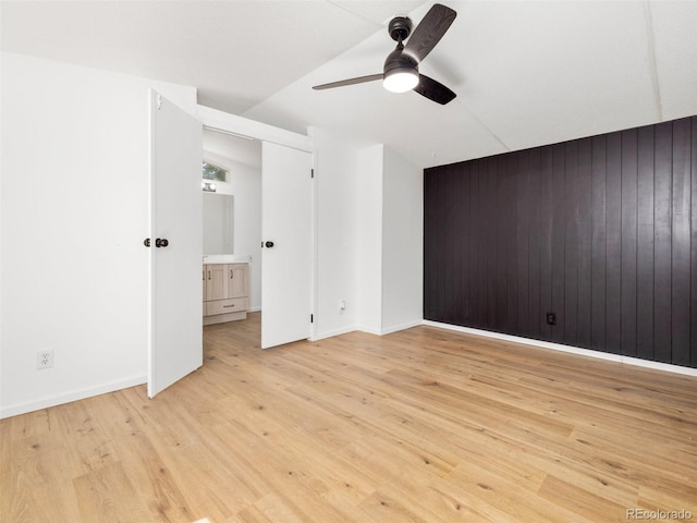 unfurnished bedroom featuring wood walls, light hardwood / wood-style flooring, and ceiling fan