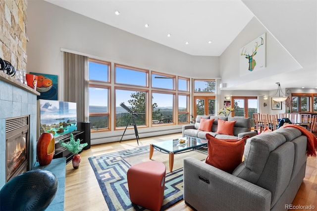 857 Pawnee Trl, Castle Rock, CO 80108 - living area featuring a baseboard radiator, a large fireplace, wood finished floors, a towering ceiling, and recessed lighting