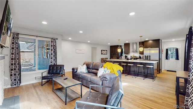 living room with recessed lighting, visible vents, baseboards, and light wood-style flooring