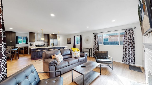 living area featuring plenty of natural light, beverage cooler, recessed lighting, and light wood finished floors