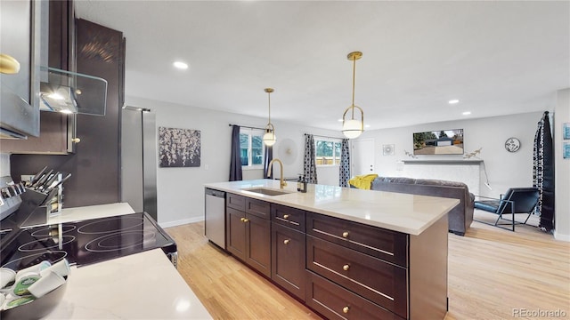 kitchen featuring pendant lighting, light wood-style flooring, a sink, appliances with stainless steel finishes, and light countertops