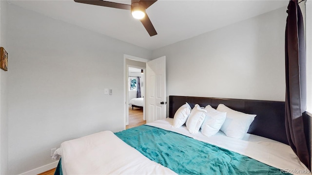 bedroom with a ceiling fan, wood finished floors, and baseboards