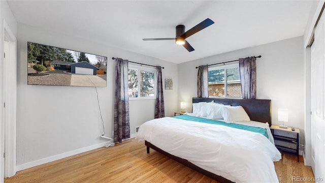 bedroom featuring light wood-style flooring, multiple windows, baseboards, and ceiling fan