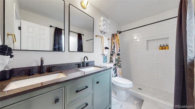 bathroom with double vanity, toilet, a tile shower, and a sink