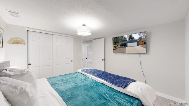 carpeted bedroom with visible vents, baseboards, a textured ceiling, and a closet