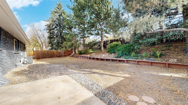 view of yard featuring a fenced backyard, central AC unit, and a patio