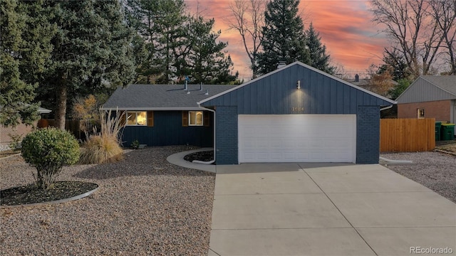 view of front of home featuring brick siding, driveway, an attached garage, and fence