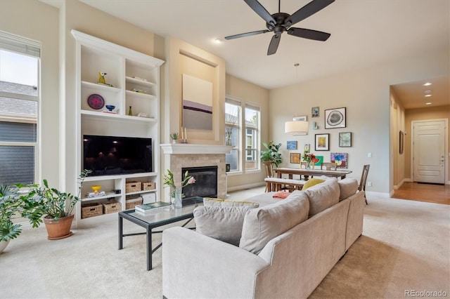 living area featuring light colored carpet, ceiling fan, a glass covered fireplace, baseboards, and recessed lighting