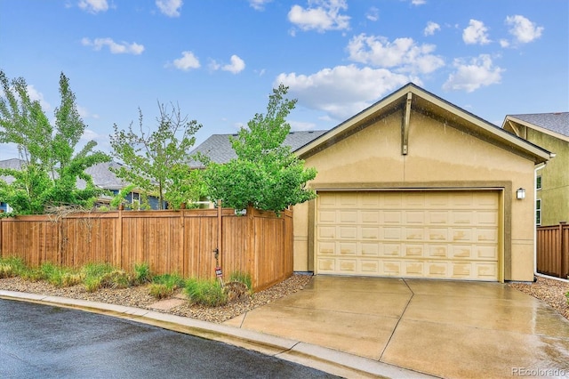 garage featuring fence and concrete driveway