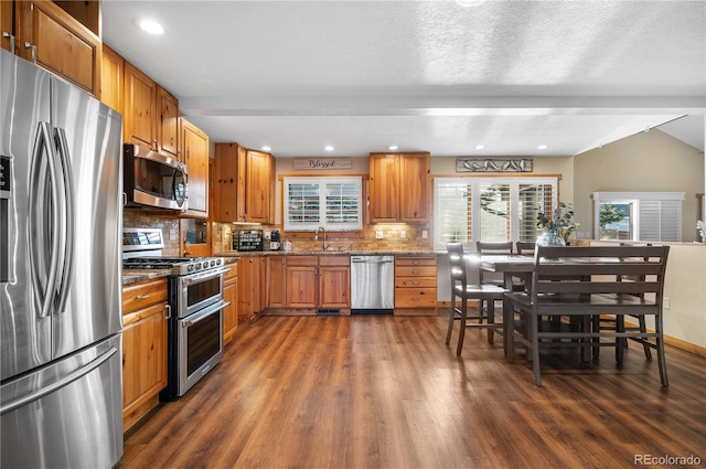 kitchen featuring appliances with stainless steel finishes, sink, backsplash, and dark hardwood / wood-style flooring