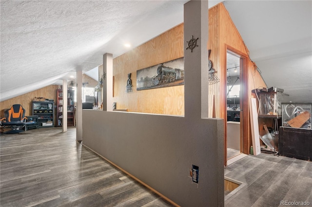 hall featuring vaulted ceiling, dark hardwood / wood-style floors, and a textured ceiling