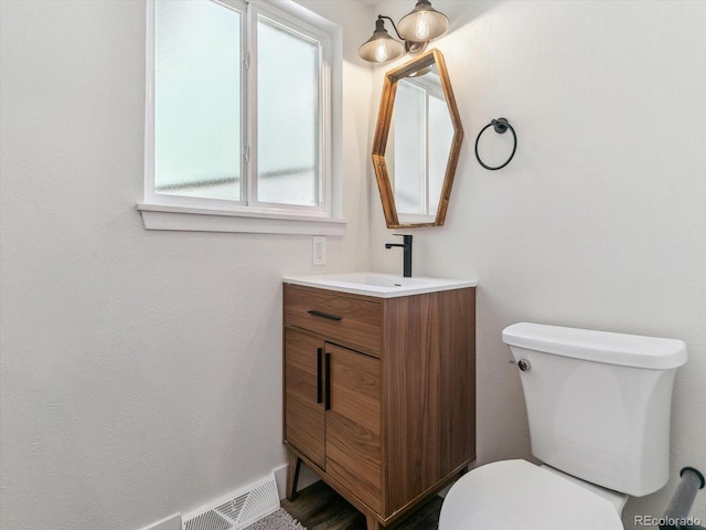 bathroom featuring vanity, a healthy amount of sunlight, and toilet