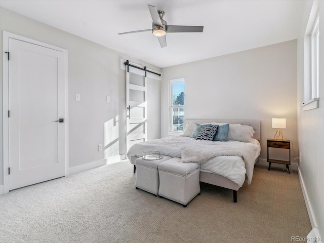 bedroom featuring ceiling fan, a barn door, and carpet floors