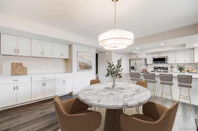 dining space with dark wood-type flooring and recessed lighting