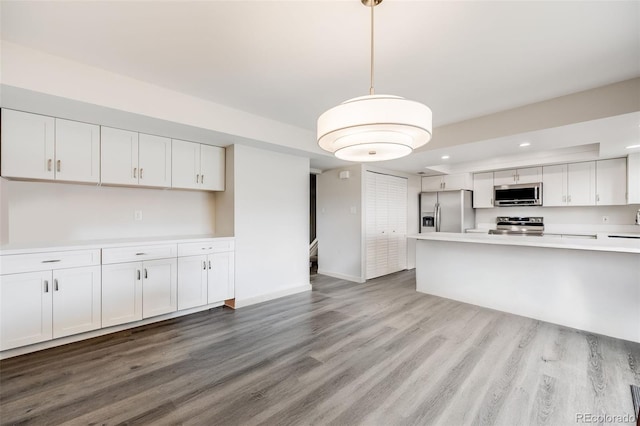 kitchen featuring recessed lighting, stainless steel appliances, wood finished floors, white cabinetry, and light countertops