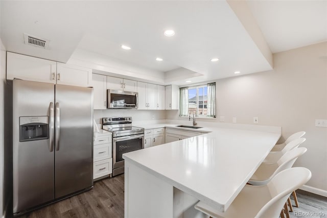 kitchen with stainless steel appliances, light countertops, visible vents, a peninsula, and a kitchen bar