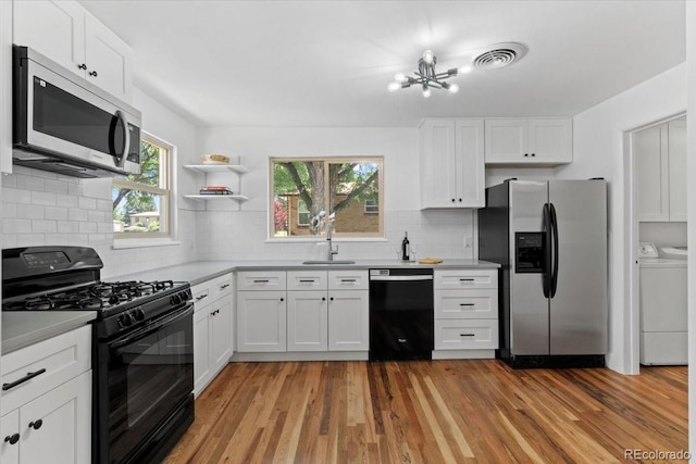 4125 Pierce St, Wheat Ridge, CO 80033 - kitchen with black appliances, separate washer and dryer, light wood-style flooring, and white cabinets