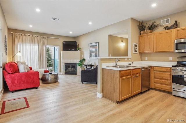 3847 Mossy Rock Dr Unit 104, Highlands Ranch, CO 80126 - kitchen with appliances with stainless steel finishes, a sink, open floor plan, a peninsula, and light wood-style floors