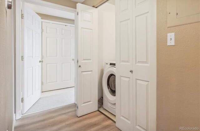 3847 Mossy Rock Dr Unit 104, Highlands Ranch, CO 80126 - clothes washing area with light wood finished floors, washer / clothes dryer, and a textured wall