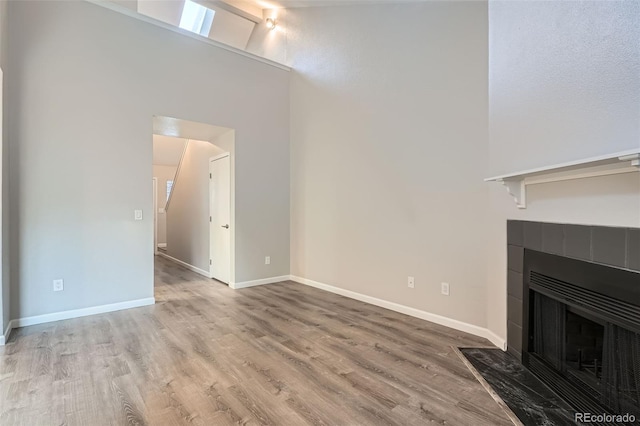 unfurnished living room with a fireplace, high vaulted ceiling, and light hardwood / wood-style flooring