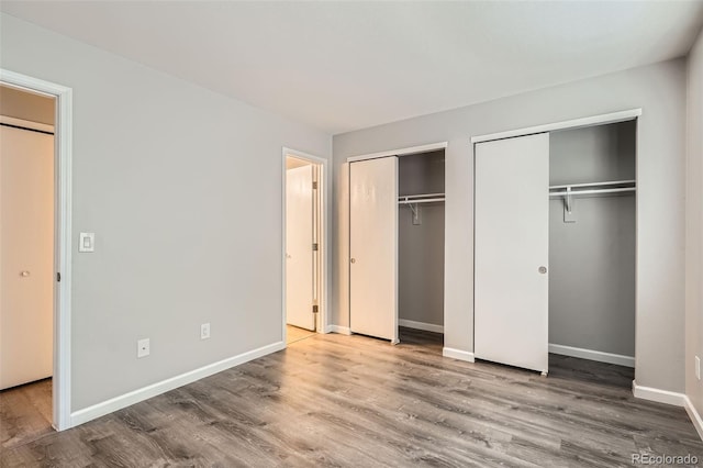 unfurnished bedroom with two closets and hardwood / wood-style flooring