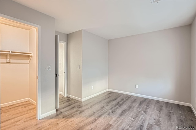 unfurnished bedroom featuring a walk in closet, a closet, and light hardwood / wood-style flooring