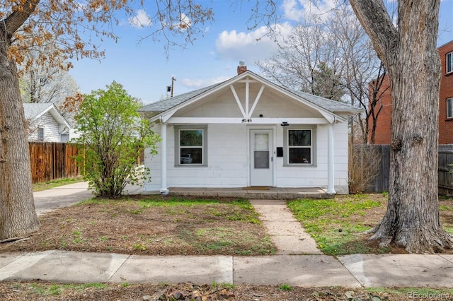 4046 S Bannock St, Englewood, CO 80110 - bungalow-style home featuring a shingled roof, fence, covered porch, and a chimney