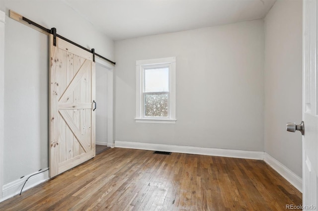 4046 S Bannock St, Englewood, CO 80110 - unfurnished bedroom with a barn door, visible vents, baseboards, and hardwood / wood-style floors
