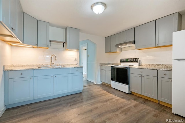 4046 S Bannock St, Englewood, CO 80110 - kitchen with a sink, white appliances, under cabinet range hood, wood finished floors, and backsplash