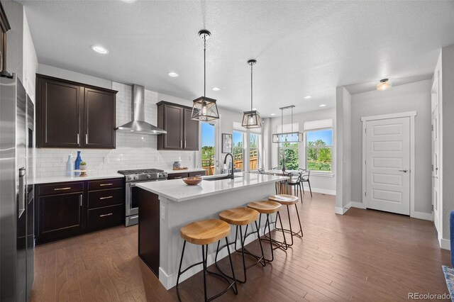 6700 Clay St, Denver, CO 80221 - kitchen featuring wall chimney exhaust hood, stainless steel range with gas cooktop, refrigerator with ice dispenser, light countertops, and a breakfast bar