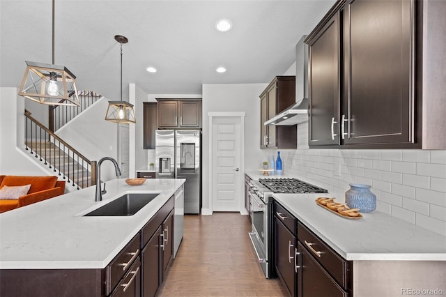 6700 Clay St, Denver, CO 80221 - kitchen with appliances with stainless steel finishes, dark brown cabinetry, wall chimney range hood, wood finished floors, and backsplash