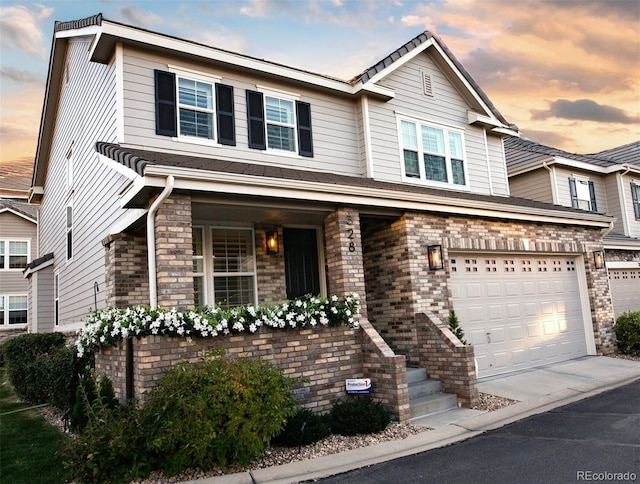 view of front of home featuring a garage, concrete driveway, and brick siding