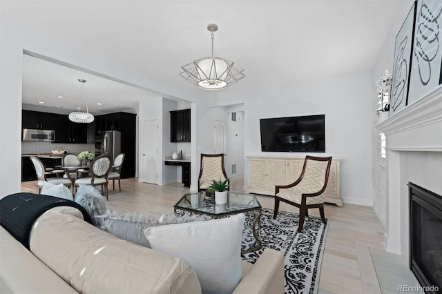 living room with light wood finished floors, a fireplace with flush hearth, and baseboards